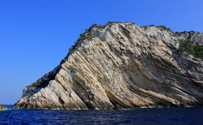 A dramatic view of the rugged coastline of Biševo island, Croatia, with steep cliffs and clear blue waters.