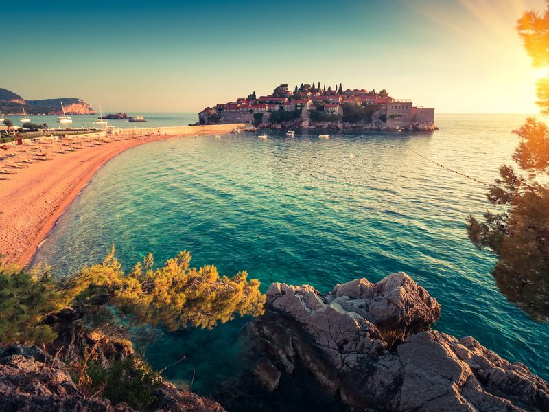 A panoramic view of the beautiful Budva Riviera, showcasing the luxury resort island of Sveti Stefan and its surrounding turquoise waters.