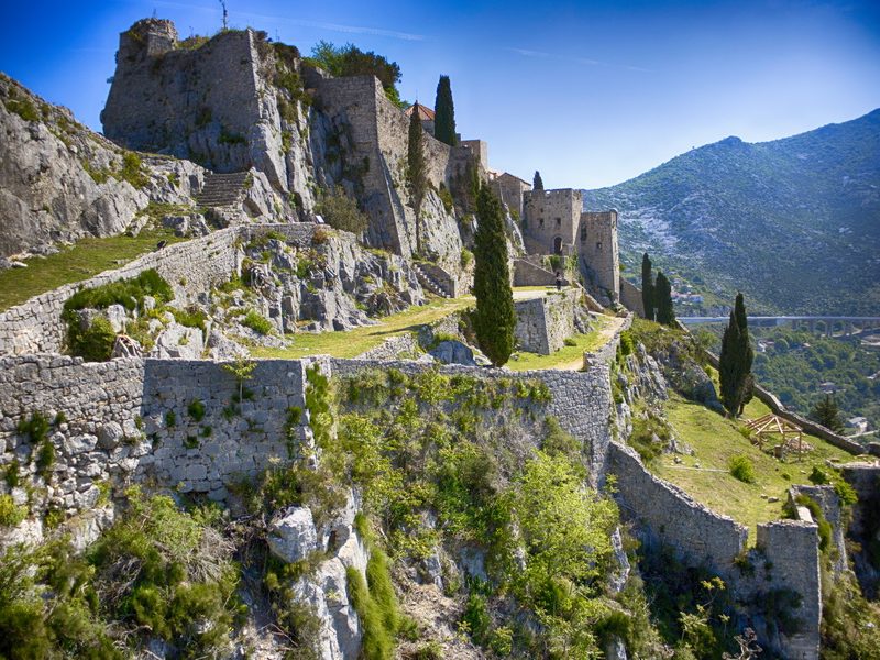 A majestic view of Klis Fortress, a historic fortress perched on a hilltop overlooking the surrounding landscape.