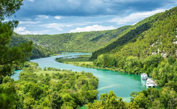 A scenic view of the turquoise waters of the Krka National Park, surrounded by dense forests.