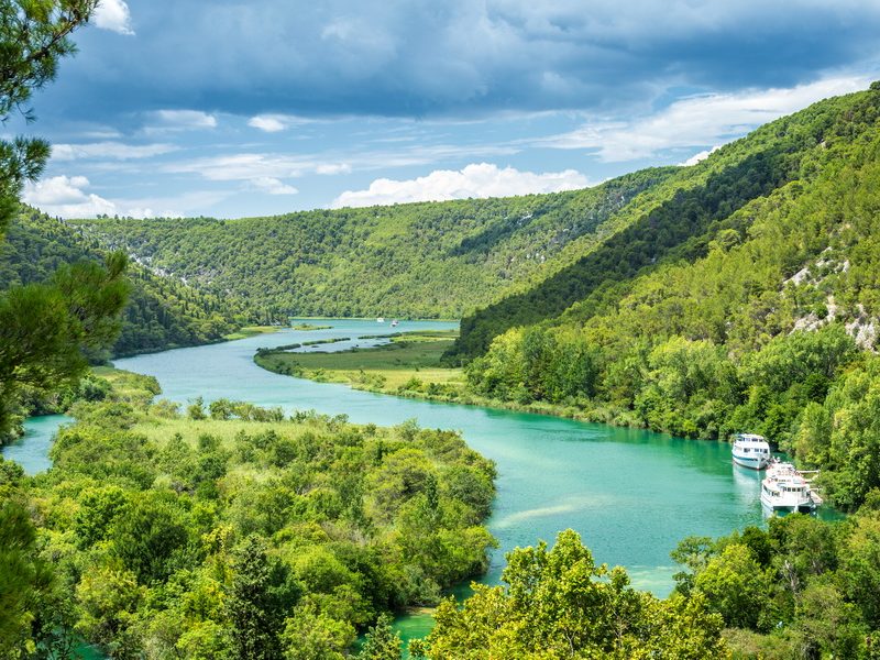 A scenic view of the turquoise waters of the Krka National Park, surrounded by dense forests.