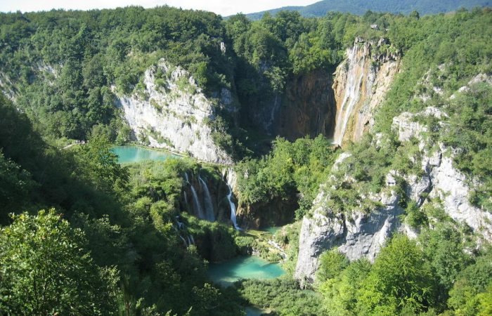 A stunning aerial view of Plitvice Lakes, with turquoise lakes nestled among towering cliffs and dense forests.