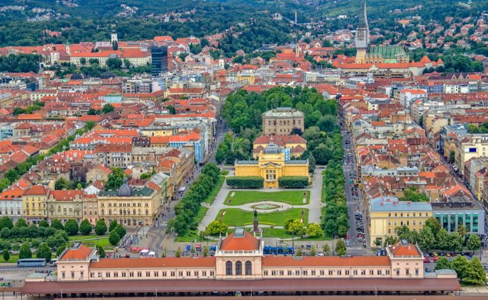 An aerial view of Zagreb, Croatia, showcasing the city's historic center, including the Main Railway Station and a park.