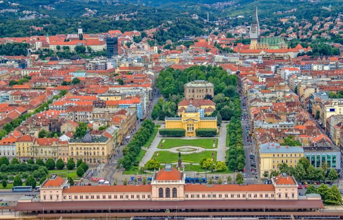 An aerial view of Zagreb, Croatia, showcasing the city's historic center, including the Main Railway Station and a park.