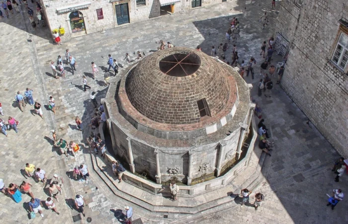 Aerial view of the Large Onofrio’s Fountain in Dubrovnik’s Old Town, surrounded by historic stone buildings and bustling visitors - iconic landmark and must-see attraction in Dubrovnik, Croatia.
