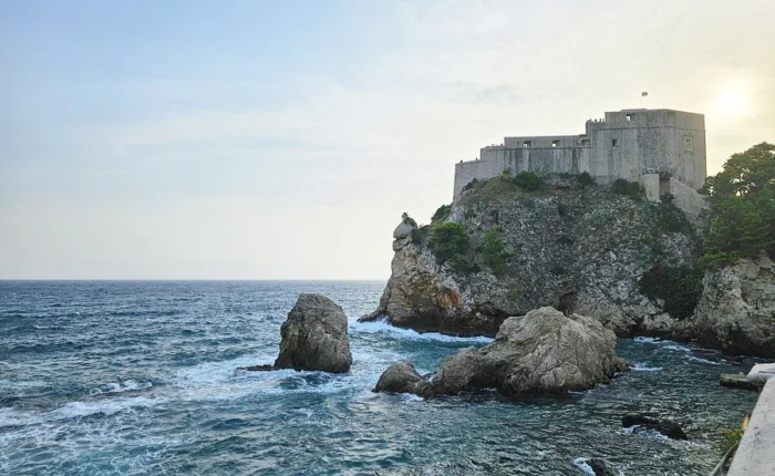 Fort Bokar in Dubrovnik, recognized by fans as Game of Thrones’ Blackwater Bay, rises above rocky cliffs and the churning Adriatic sea at sunset.