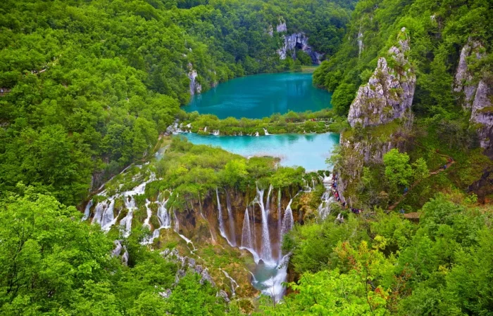 Classic view of Plitvice’s upper and lower lakes with main multi-level waterfalls, rich forest, and turquoise water in Croatia’s UNESCO national park.