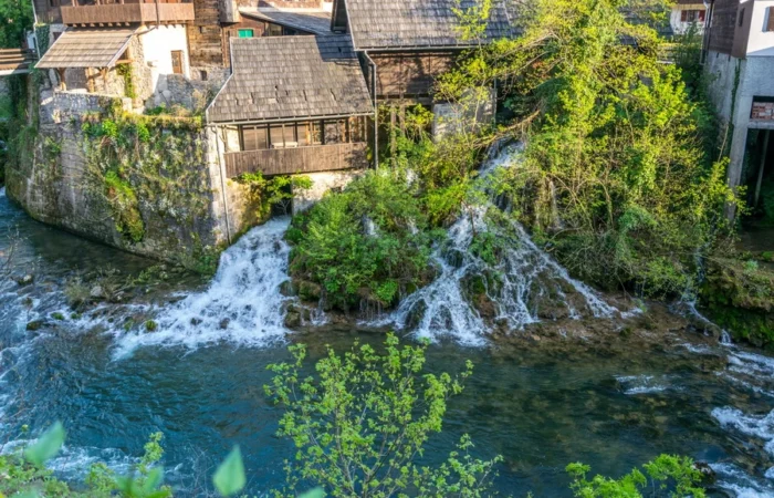 Traditional wooden watermills perched above cascading waterfalls and clear blue rivers in the fairytale village of Rastoke, Slunj, Croatia.