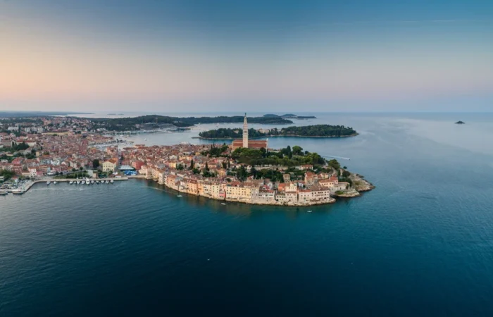 Aerial view of Rovinj Old Town with the Church of St. Euphemia on a peninsula, surrounded by blue Adriatic waters in Istria, Croatia.