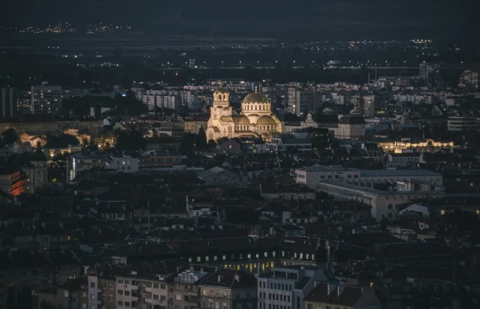 Sofia’s Alexander Nevsky Cathedral illuminated at night, standing out against the cityscape of Bulgaria’s capital under a dark sky.