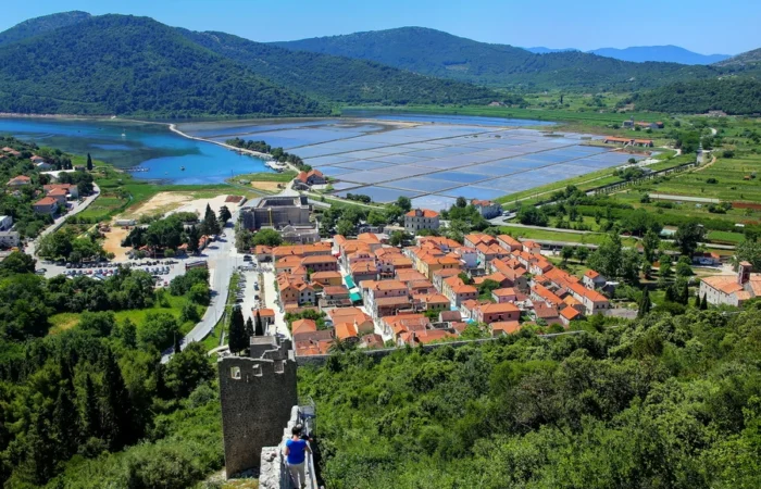 Aerial view of Ston, Croatia, with its medieval town, extensive salt pans, and ancient fortress walls stretched across the landscape on the Pelješac peninsula.