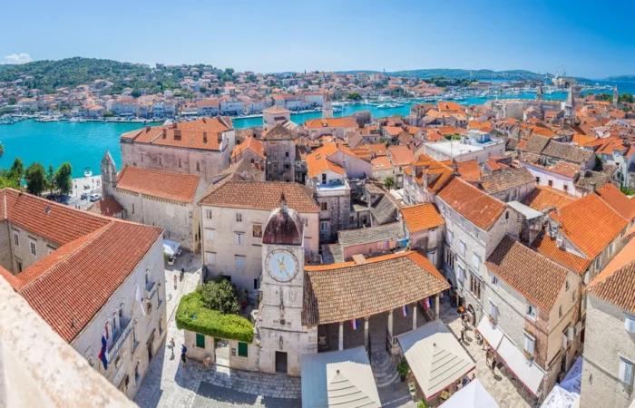 Panoramic aerial view over Trogir’s UNESCO old town with the clocktower, red rooftops, blue Adriatic Sea, and historic waterfront, Dalmatia, Croatia.