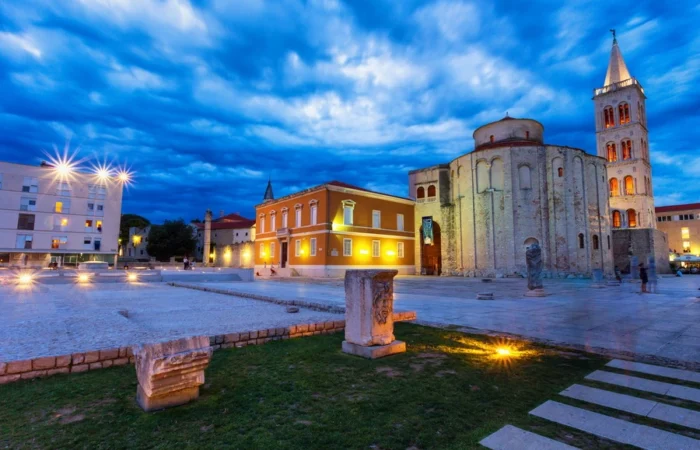 The illuminated Church of St. Donatus and surrounding Roman Forum stones glow at dusk in Zadar’s old town, Croatia.