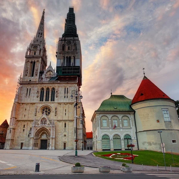 Zagreb Cathedral’s soaring neo-Gothic towers and baroque Kaptol fortifications set against a colorful sunset sky in Croatia’s capital city.