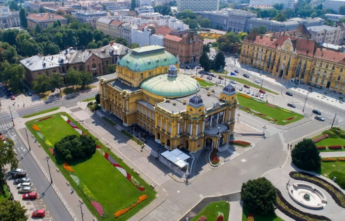 Panoramic aerial view of Zagreb’s Old Town with its dense cluster of red-tiled roofs, tree-lined streets, and historic buildings blending with green parks.